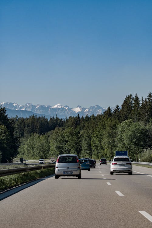 Cars on Road Near Trees and Mountains