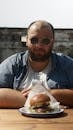 Man Sitting on Table with Hamburger