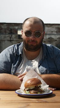 A man wearing sunglasses enjoying a delicious burger outdoors on a sunny day in Berlin.