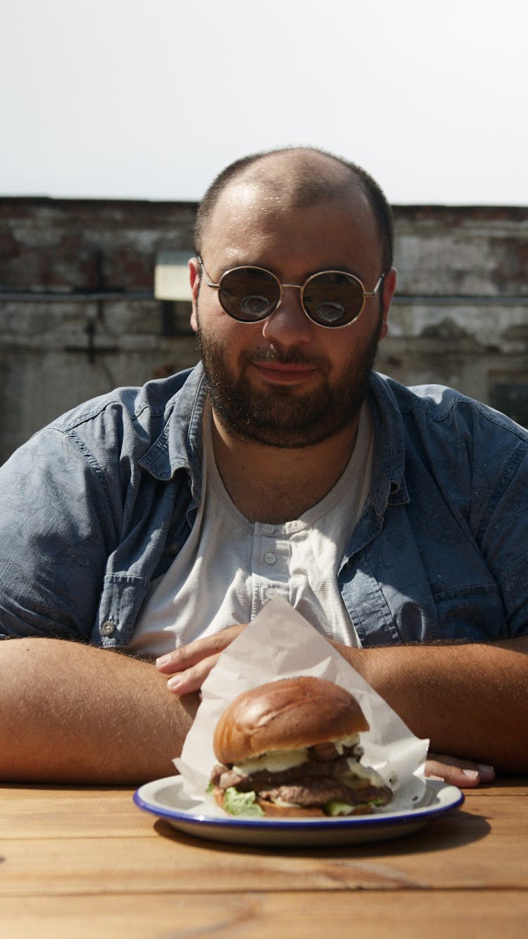 Man Sitting On Table With Hamburger