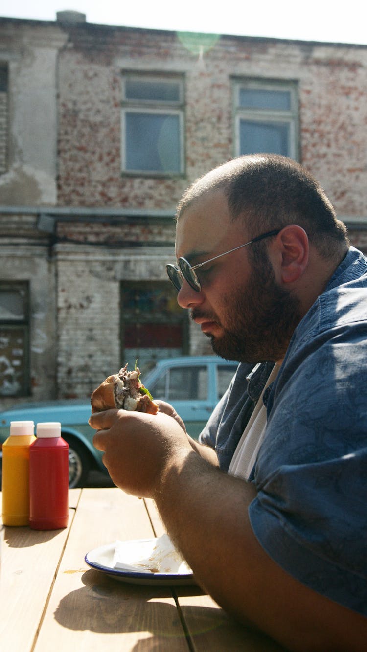 Man In Blue Button Up Shirt Holding Hamburger