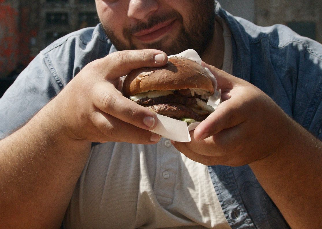 A man savoring a delicious hamburger at an outdoor setting in Australia.