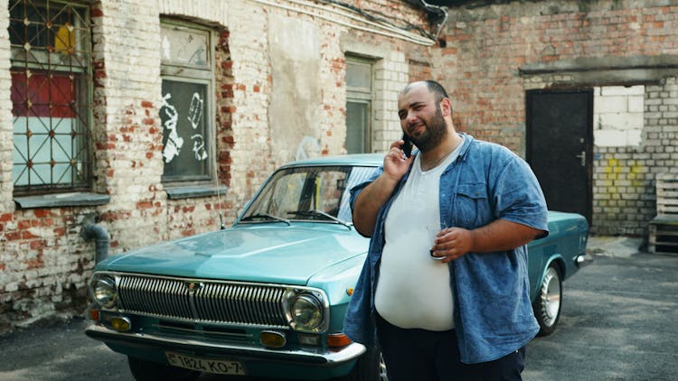 Man Talking On The Phone Near Parked Car