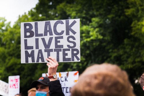Free Outdoor protest scene in Munich with a focus on a Black Lives Matter sign held by a participant. Stock Photo