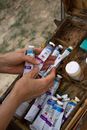 Crop female artist choosing oil paints in nature