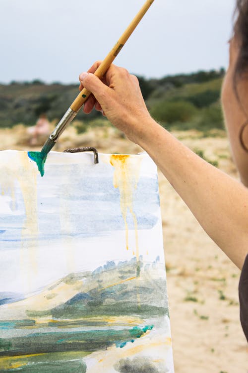Artist with brush drawing nature on canvas