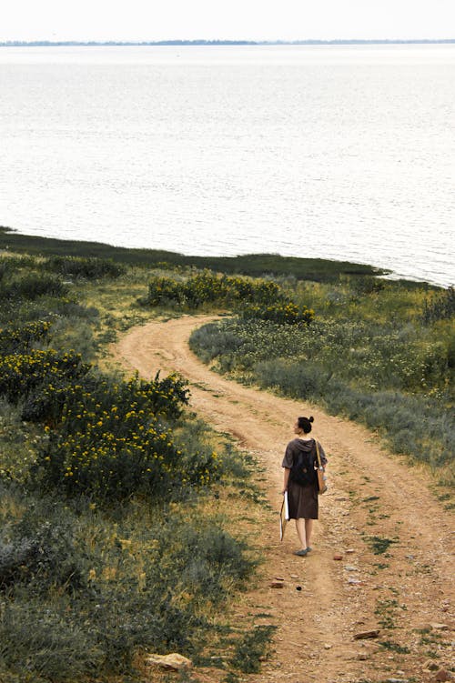 Free Woman standing on path near river and enjoying scenery Stock Photo