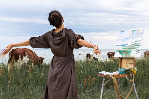 Young woman with arms outstretched painting nature