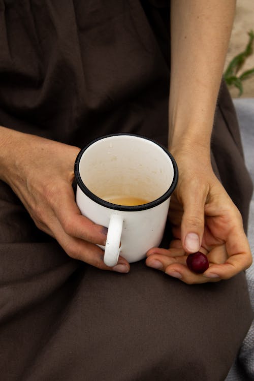 Free Woman with hot drink and cherry resting in nature Stock Photo