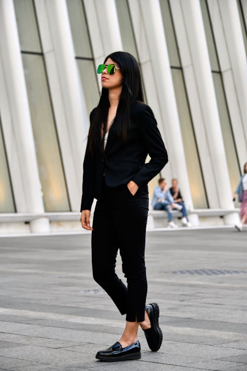 Woman in Black Blazer and Pants Standing on Gray Pavement