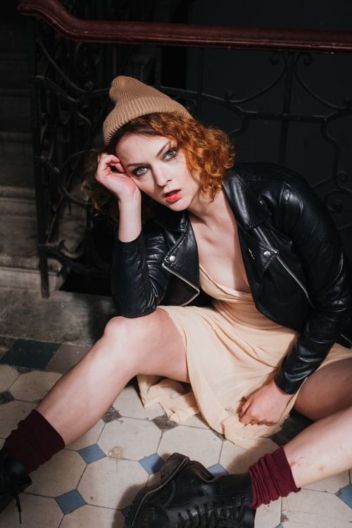 Woman in Black Leather Jacket and Brown Skirt Sitting on Black Floor ...