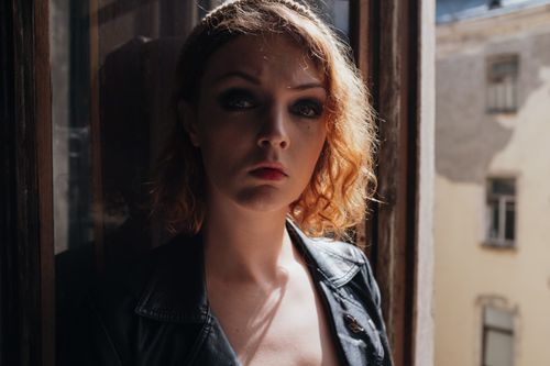 Free Stylish woman with red curls in a vintage setting by a window. Stock Photo