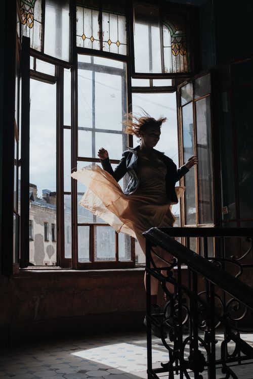 Free A woman in motion, captured in silhouette against a vintage window, creates a dynamic atmosphere. Stock Photo