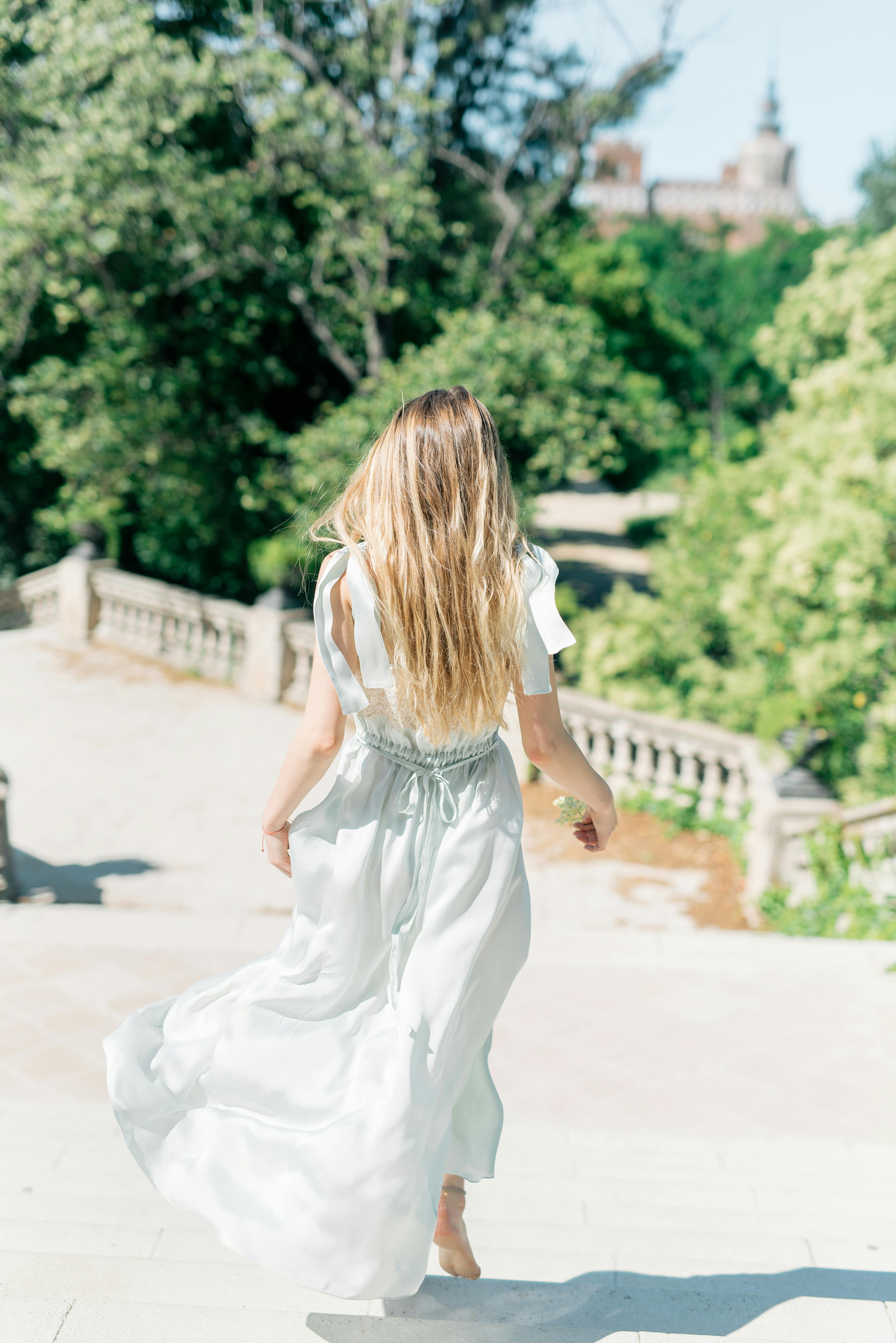 back view of a woman in white dress walking down the steps