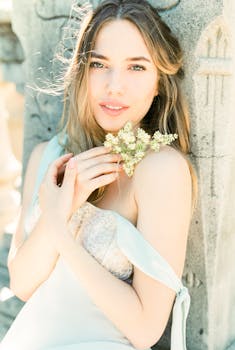 一位身着浅色连衣裙的美丽女子手持精致的野花，显得优雅动人