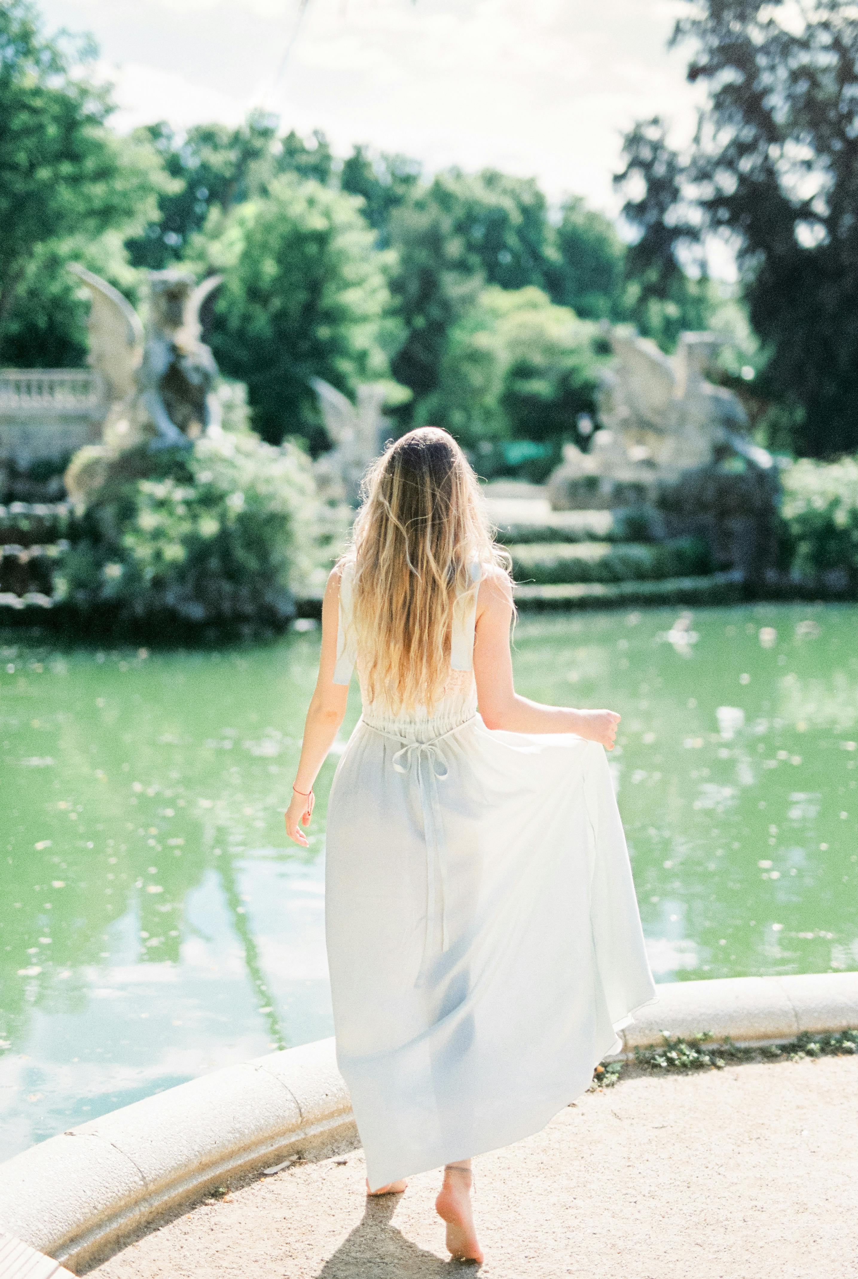 湖边风景如画，一名身穿飘逸白裙的女子宁静伫立