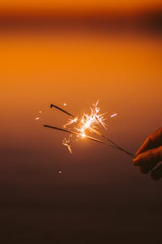Stunning close-up of sparklers igniting against a warm golden background, evoking festive celebration.