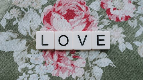 A Word Love Spelled with White Letter Blocks on a Floral Textile