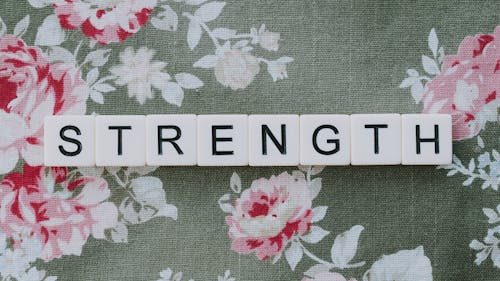 Free A Word Strength Spelled with White Letter Blocks on a Floral Textile Stock Photo