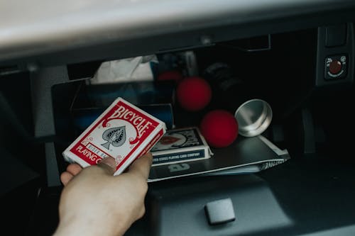 A Person Holding a Pack of Bicycle Playing Cards from a Glove Compartment