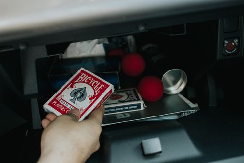 Free Close-up of a hand retrieving Bicycle playing cards from a car glove compartment with red juggling balls. Stock Photo