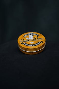 Round tin of Dapper Dan hair paste against a dark background.