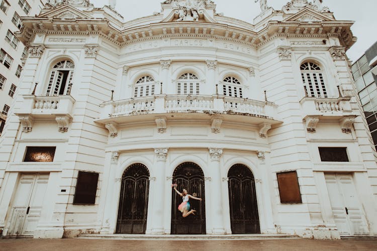 Unrecognizable Woman Jumping Near Old Building Facade