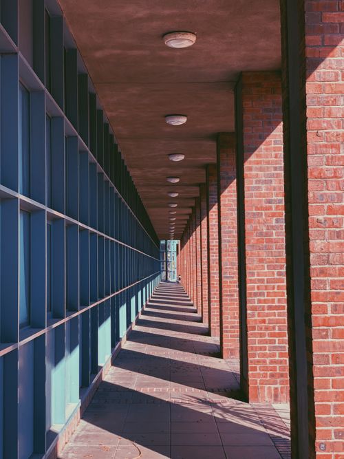 Free Long shadowed corridor with bricks and symmetry, creating an abstract architectural perspective. Stock Photo