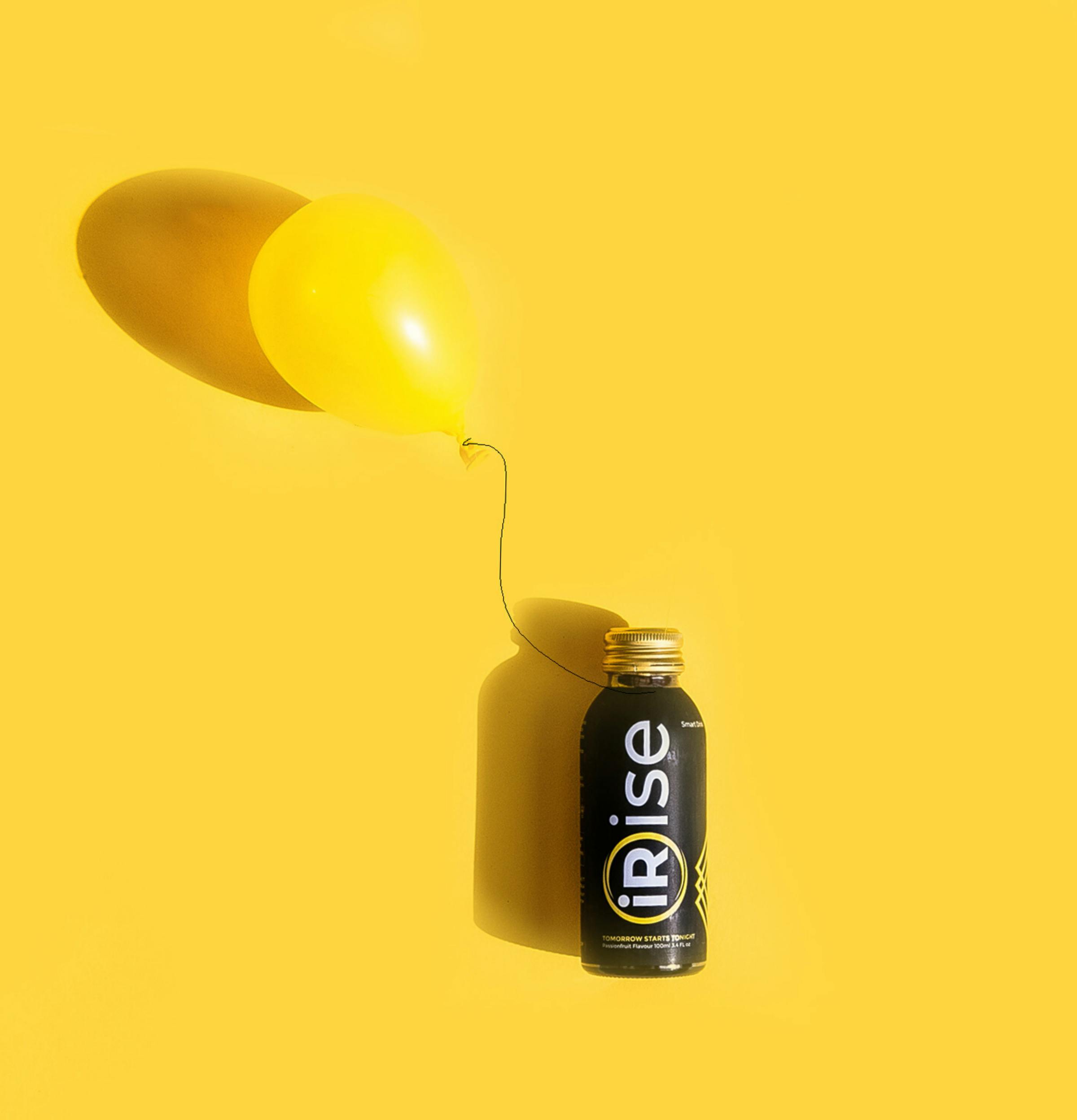 Minimalistic yellow-themed studio shot of a beverage bottle with a balloon, ideal for advertising and marketing.