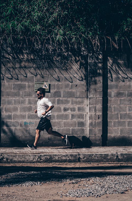 Free Concentrated ethnic man jogging on roadside Stock Photo