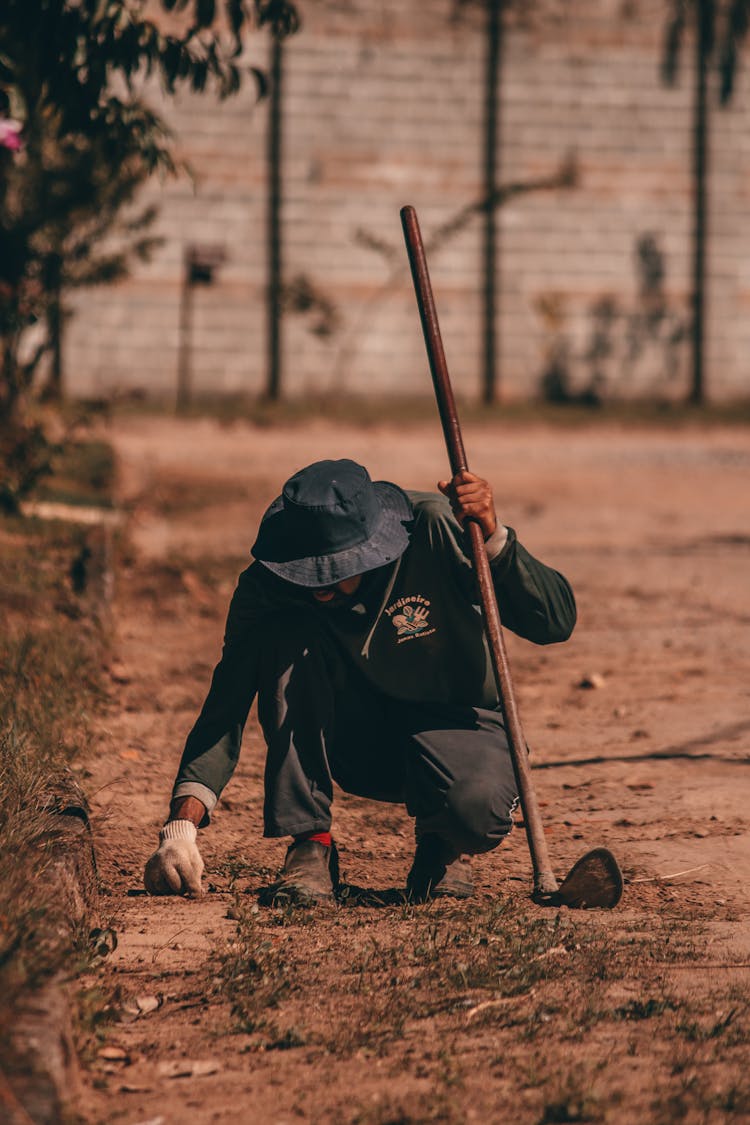 Faceless Ethnic Man Weeding Soil And Removing Garden Weeds