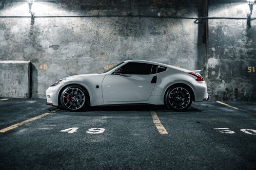 Contemporary style automobile with luxury wheels and tinted windscreen on pavement near shabby wall
