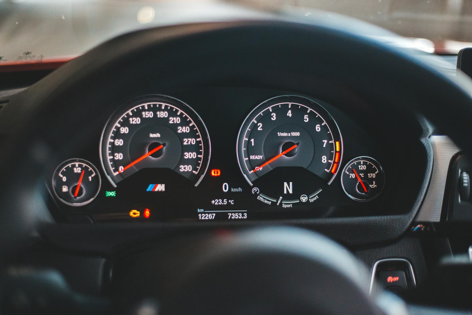 Close-up of a luxury car dashboard display with illuminated gauges and speedometer.