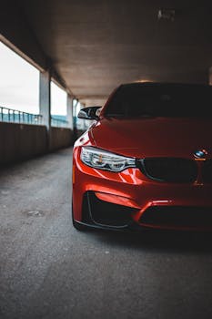 Parked red car with shiny headlights and tinted windshield on asphalt parking lot