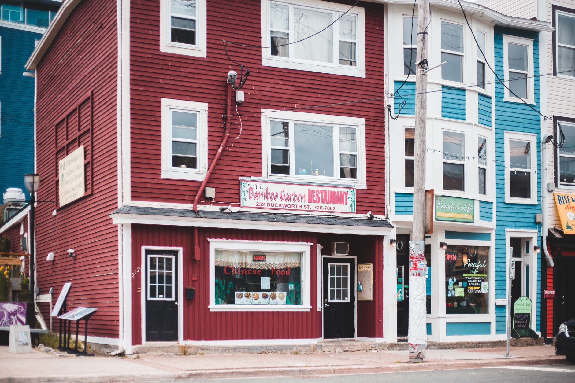 Vibrant street view of red and blue buildings hosting diverse restaurants and cafes.