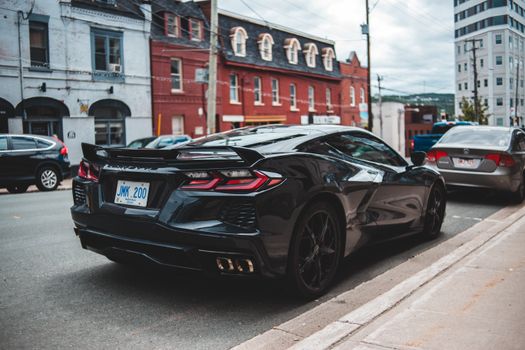 Luxury car with total black bodywork and wheels on asphalt street in aged city