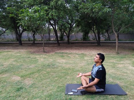 A man meditates on a yoga mat in a serene park in New Delhi, India.