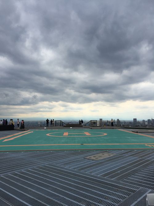 Free People standing on a rooftop helipad in Tokyo, Japan under dramatic overcast skies. Stock Photo