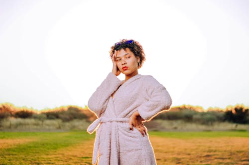 Pensive young African American lady in robe on grassy field