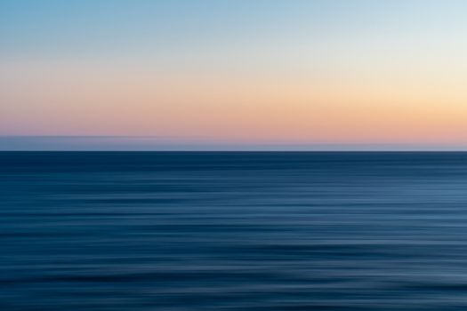 Serene ocean scene with a beautiful gradient sunset sky over calm waters.