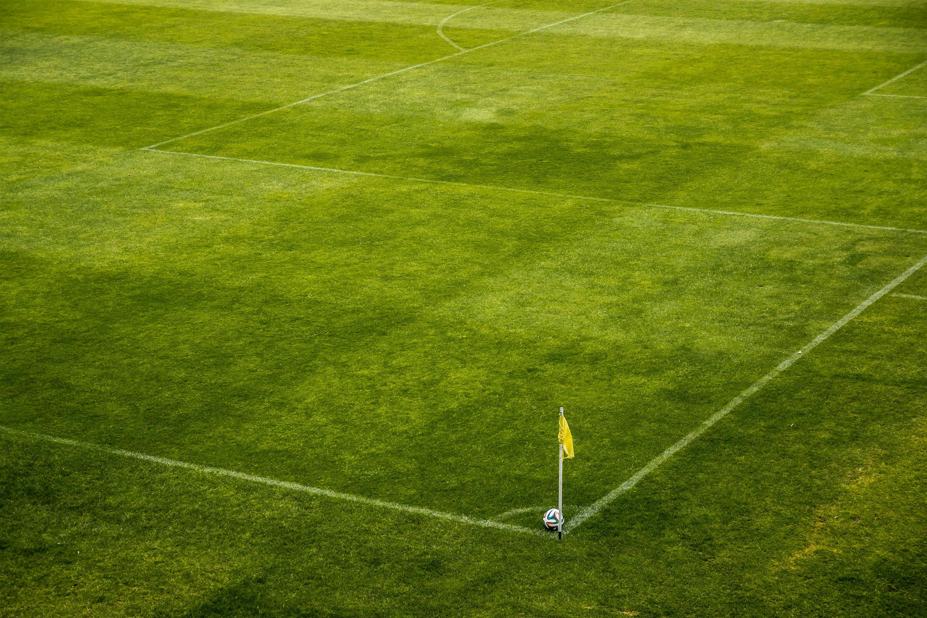 Jogador de futebol ou futebol na parede branca com grama. ângulo amplo.