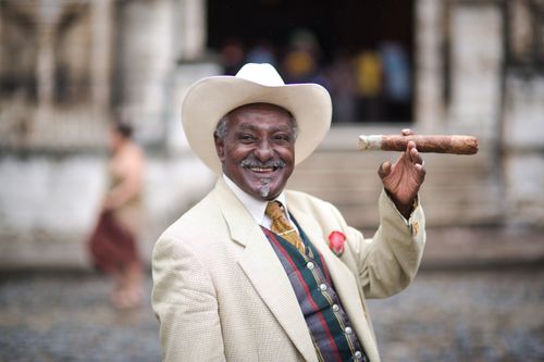Free Elderly man in Havana, Cuba, holding a cigar, smiling, wearing a hat and suit jacket. Stock Photo