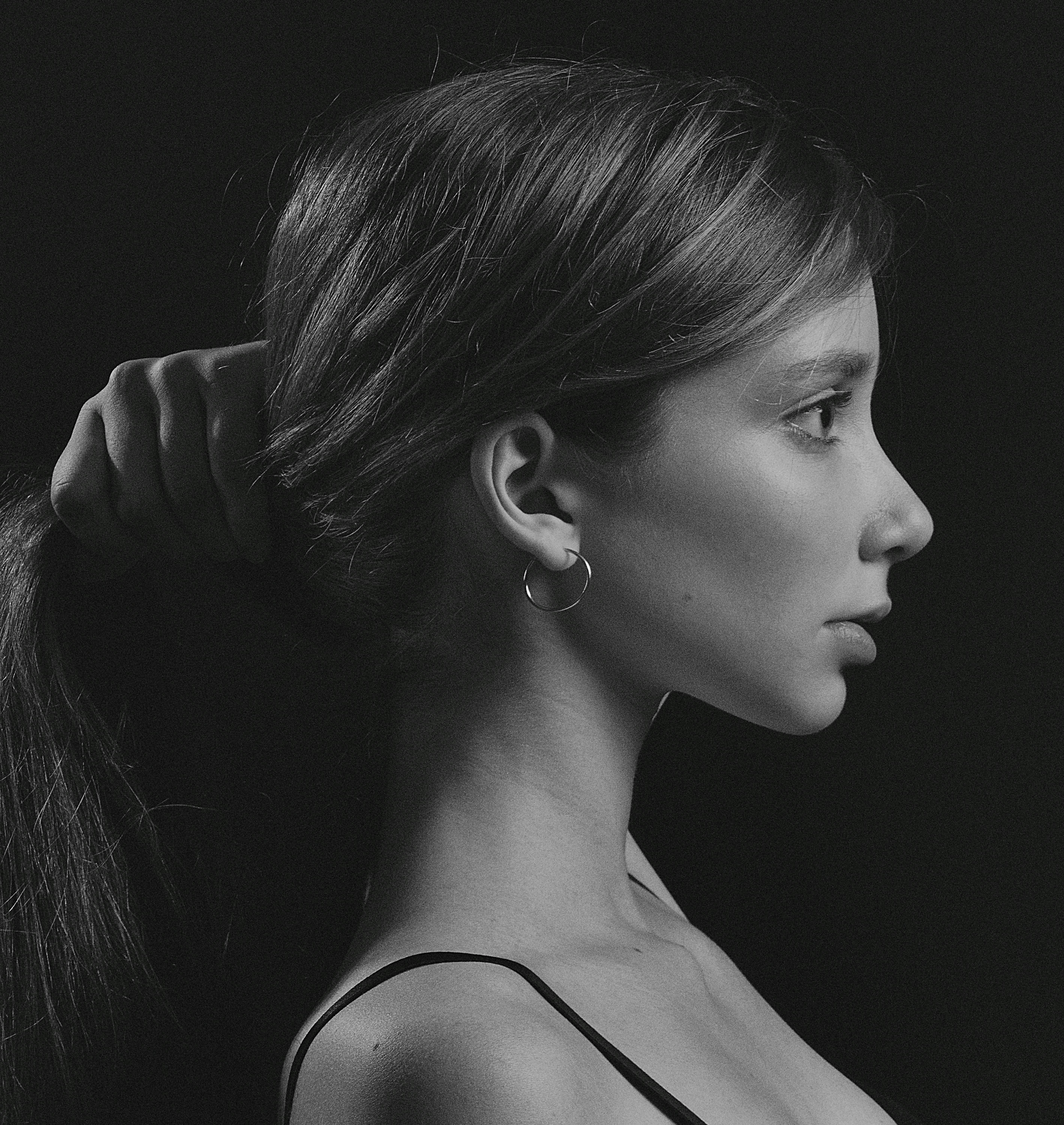 A striking black and white side profile of a woman holding her hair, photographed in Kyiv.