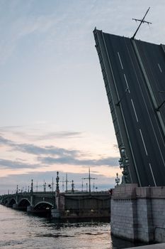 这张照片捕捉了圣彼得堡涅瓦河上标志性的开放吊桥在黄昏时分的景象