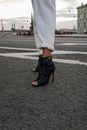 Person in White Pants and Black Boots Standing on Gray Asphalt Road
