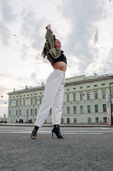 Woman dancing on urban street with classic architecture backdrop.
