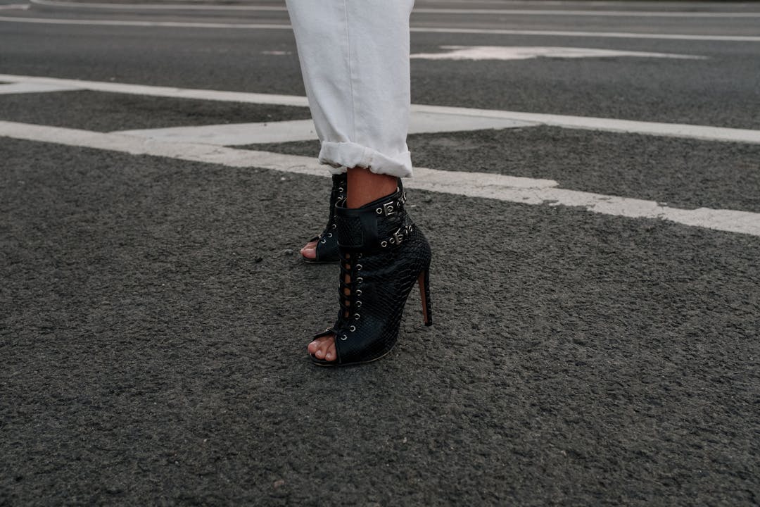 Close-up of a stylish black high heel on an urban street, highlighting modern fashion.