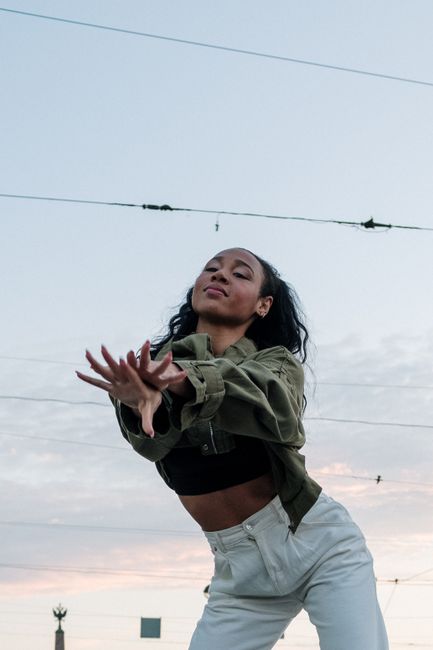 A young woman showcases her freestyle dance moves in an urban outdoor setting during a beautiful dusk.