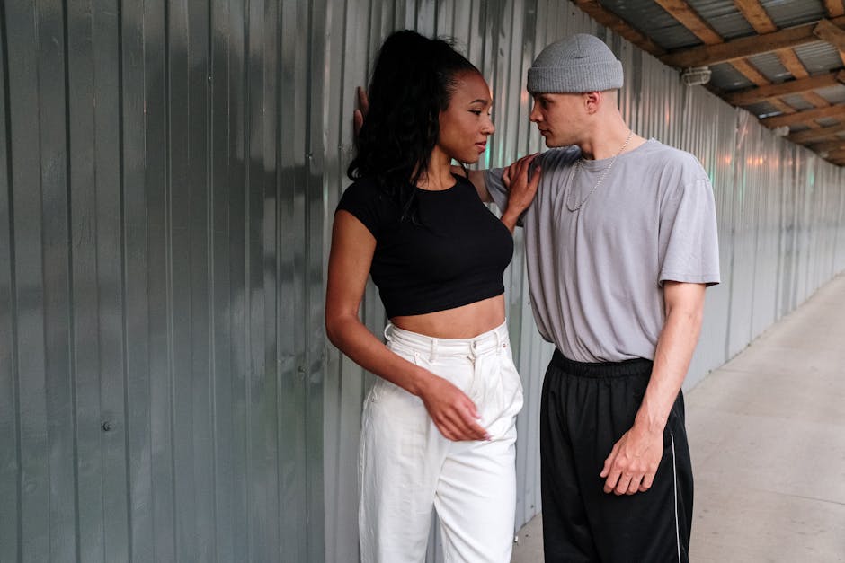 Man in Blue Polo Shirt and White Pants Standing Beside Woman in Black Shirt