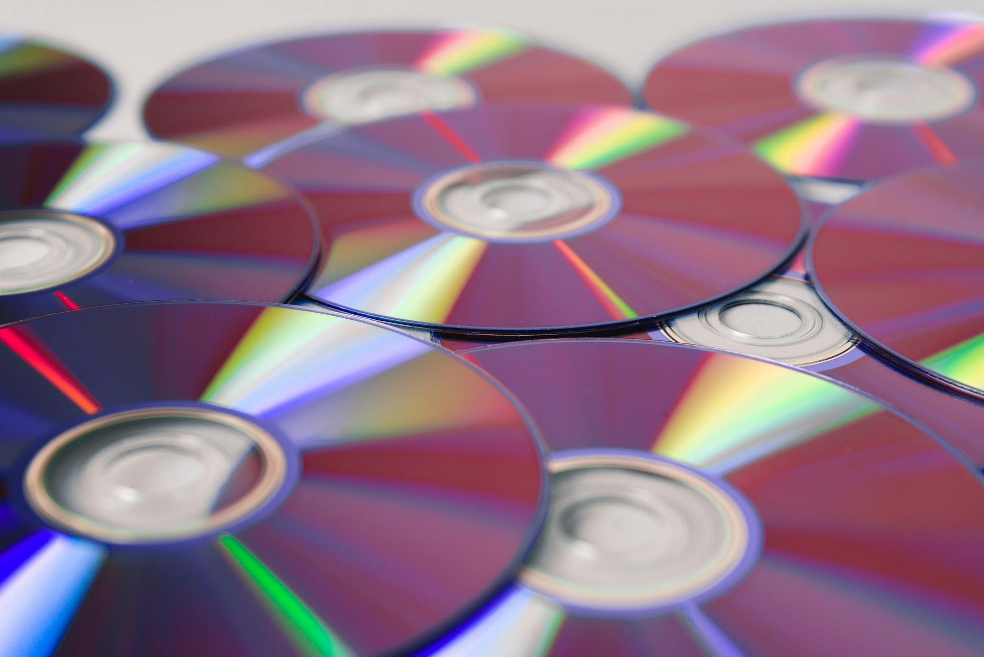 Stack of colorful CDs reflecting light, showcasing vibrant refractions and round patterns.